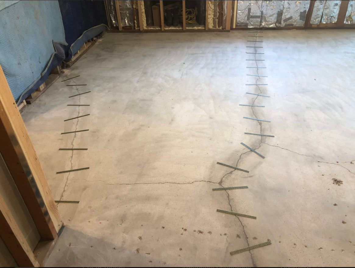 Reinforcement strips positioned across cracks in an interior concrete floor